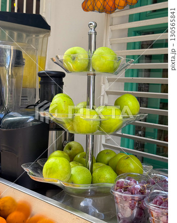Fresh green apples arranged on a multi-level glass stand. Nutrition, freshness, and fruit display in urban market. Fresh green apples arranged on a multi-level glass stand. Nutrition, freshness, and fruit display in urban market. 130565841