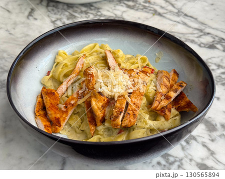 Tagliatelle pasta with grilled chicken and parmesan in creamy sauce. Cuisine, flavor, and gourmet dining in restaurant lifestyle and food culture. 130565894