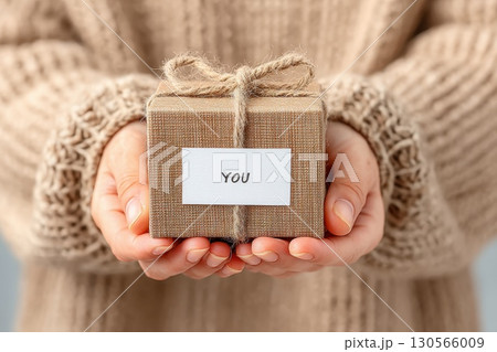 Elegant Wrapped Box Holding with Cozy Knit Sweater Background and Simple You Tag 130566009