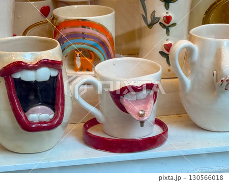 Ceramic cups with playful mouth designs and colorful details. Art, humor, and creative design in modern lifestyle and consumer culture. 130566018