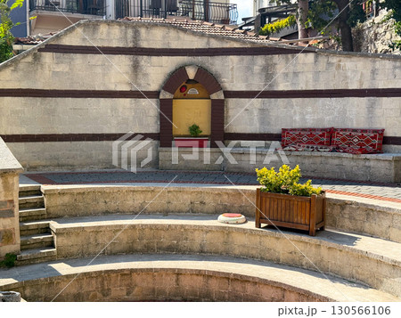 Amphitheater courtyard with stone benches and red patterned cushions. Architecture, heritage, and cultural tradition reflecting outdoor gathering, leisure, and hospitality atmosphere. Amphitheater courtyard with stone benches and red patterned cushions. Architecture, heritage, and cultural tradition reflecting outdoor gathering, leisure, and hospitality atmosphere. 130566106