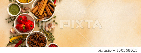 A warm display of spices and herbs on a beige background, each adding rich aromas and flavors, perfect for enhancing recipes, banner 130568015