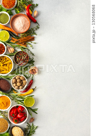 Various cooking spices and herbs spread across a neutral gray background, showcasing their rich, natural tones, top view and copy space 130568068