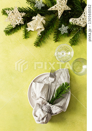 A top view of a Christmas table setting featuring an empty plate with napkin and cutlery, festive spruse and silver tree decorations on a bright green background A top view of a Christmas table setting featuring an empty plate with napkin and cutlery, festive spruse and silver tree decorations on a bright green background 130568082