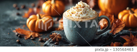 Embrace the warmth of autumn with a steaming pumpkin spice latte topped with whipped cream, surrounded by decorative pumpkins and colorful fall leaves on a soft blanket, banner 130568463