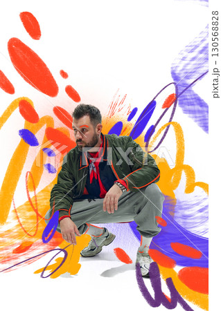 Creative artwork. Male model crouching in casual streetwear with colorful graffiti inspired background 130568828