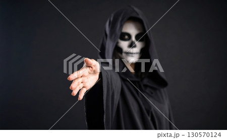 A single woman in a black nun's costume with a hood and mask poses in a studio, her dark eyes looking out from the shadows A single woman in a black nun's costume with a hood and mask poses in a studio, her dark eyes looking out from the shadows 130570124