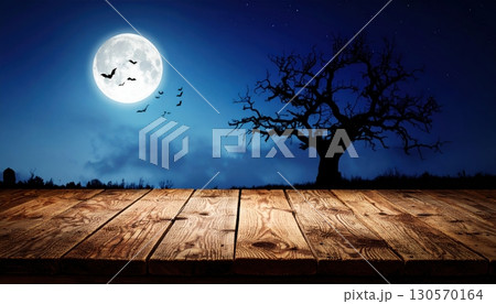 An eerie Halloween night with a silhouette of trees against an orange sky and a full moon 130570164