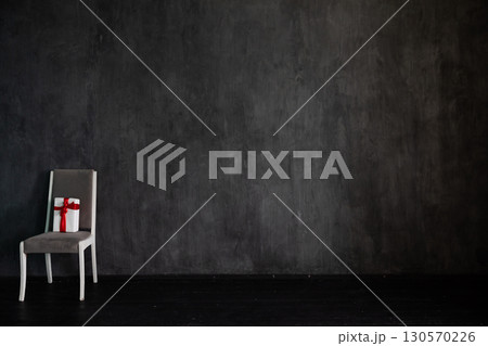 chair with gift in the interior of an empty grey room 130570226