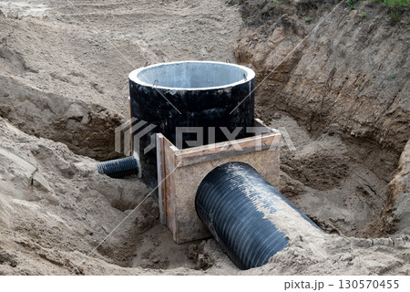 Construction site showing wastewater management system installation in a sandy trench 130570455