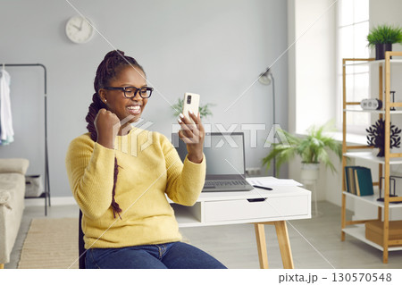Cheerful African womanmakes video call with mobile phone Cheerful African womanmakes video call with mobile phone 130570548