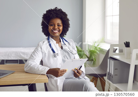 Portrait of a young african american doctor in white medical uniform looking at the camera. Portrait of a young african american doctor in white medical uniform looking at the camera. 130570560