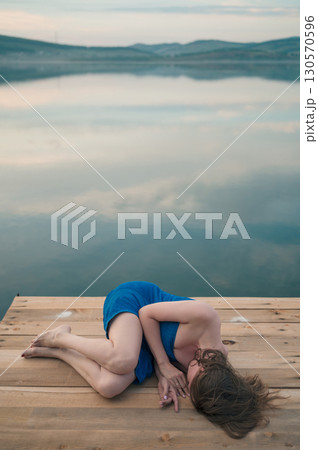 Woman in Blue Towel Sitting on Dock Woman in Blue Towel Sitting on Dock 130570596