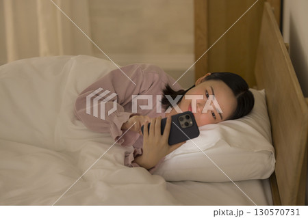 ベッドでスマホを見る女性 130570731