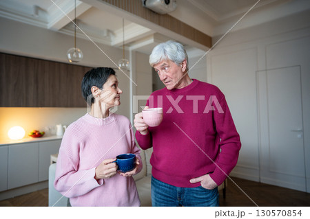 Retired wife enjoy listen to husband stories, sharing tea coffee. Happy senior couple talk at home 130570854