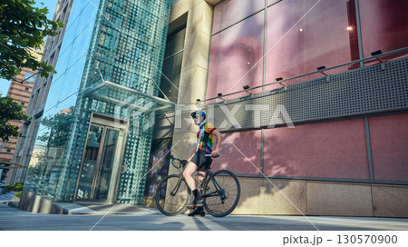 Cyclist resting with road bike near glass building in urban environment 130570900