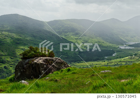 There is a pretty spot in the Gap of Dunloe in County Kerry, Ireland, where a boulder is covered with bushes and trees. It is surrounded by green hills. There is a pretty spot in the Gap of Dunloe in County Kerry, Ireland, where a boulder is covered with bushes and trees. It is surrounded by green hills. 130571045