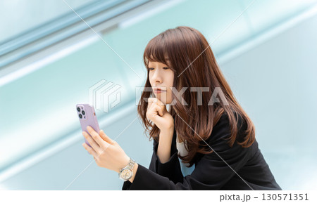 スマートフォンを見て考える女性・ビジネスウーマン 130571351