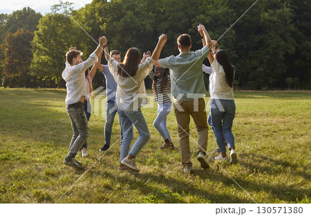 Group of young people having fun and play roundelay dancing in circle in park. Group of young people having fun and play roundelay dancing in circle in park. 130571380