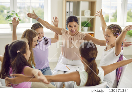 Group of school children girls sitting in a circle with psychologist and raising hands up. 130571384