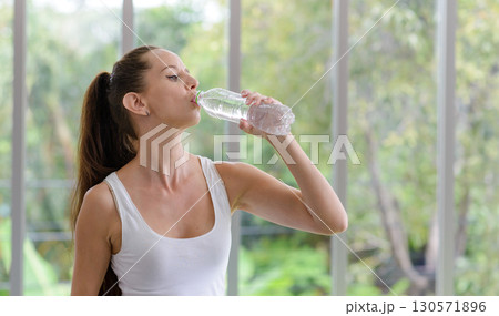 Fitness woman drinking water from bottle. Taking a break during training at gym with copy space. 130571896