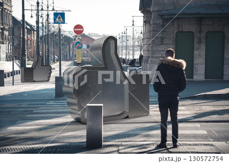 Urban pedestrian standing near oversized metallic like button, symbolizing digital interaction within metropolitan landscape. 3d compositing Urban pedestrian standing near oversized metallic like button, symbolizing digital interaction within metropolitan landscape. 3d compositing 130572754