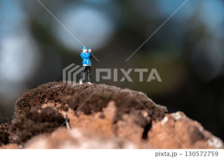 Miniature photographer capturing nature from mossy hilltop 130572759