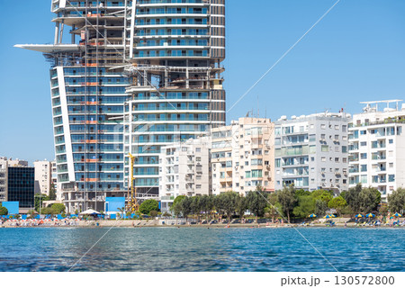 Modern skyscraper under construction towering over smaller residential buildings on Limassol coastline, Cyprus Modern skyscraper under construction towering over smaller residential buildings on Limassol coastline, Cyprus 130572800