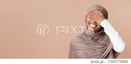 Facepalm. Cheerful Black Muslim Woman In Headscarf Covering Eyes With Hand And Laughing, Feeling Shy, Standing Over Yellow Background, Copy Space Facepalm. Cheerful Black Muslim Woman In Headscarf Covering Eyes With Hand And Laughing, Feeling Shy, Standing Over Yellow Background, Copy Space 130573066