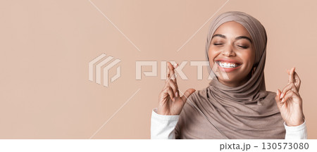 Please, please, please. Closeup portrait of dreamy black muslim girl in hijab crossing fingers, making wish, over yellow background Please, please, please. Closeup portrait of dreamy black muslim girl in hijab crossing fingers, making wish, over yellow background 130573080