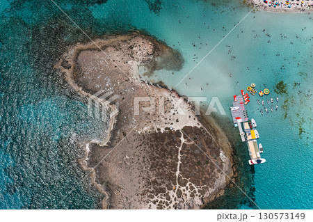 Aerial view revealing Nissi beach coastline with sunbathing visitors swimming near turquoise waters in Ayia Napa, Cyprus Aerial view revealing Nissi beach coastline with sunbathing visitors swimming near turquoise waters in Ayia Napa, Cyprus 130573149