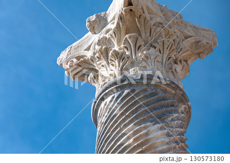 Weathered corinthian capital crowning limestone column, highlighting ancient architectural details against azure sky at Kourion archaeological site. Cyprus Weathered corinthian capital crowning limestone column, highlighting ancient architectural details against azure sky at Kourion archaeological site. Cyprus 130573180