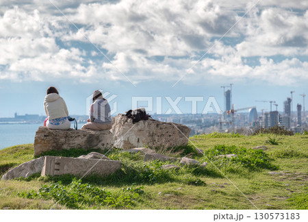 Two young women admiring Limassol skyline sitting on ancient Amathus ruins in Cyprus Two young women admiring Limassol skyline sitting on ancient Amathus ruins in Cyprus 130573183