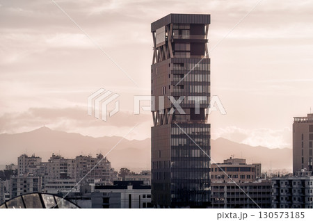 Modern skyscraper standing tall over Nicosia city skyline at dusk with mountains in the background 130573185