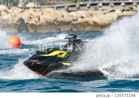Pilot riding a watercraft at high speed on the sea during a competition Pilot riding a watercraft at high speed on the sea during a competition 130573198