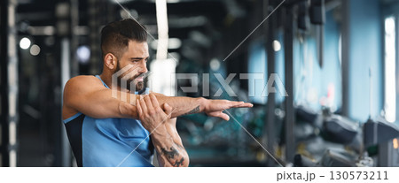 Sporty man at gym doing stretching exercises for hands, empty space, web-banner Sporty man at gym doing stretching exercises for hands, empty space, web-banner 130573211