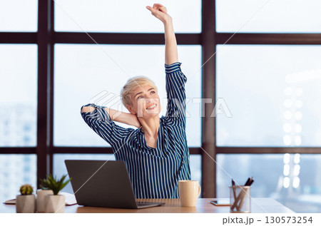 Successful Businesswoman At Laptop Stretching Hands Sitting In Modern Office. Relaxing At Workplace. Empty Space 130573254