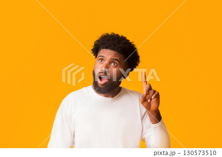Young african american shocked man having idea, pointing finger up, got problem solution, orange studio background, empty space Young african american shocked man having idea, pointing finger up, got problem solution, orange studio background, empty space 130573510