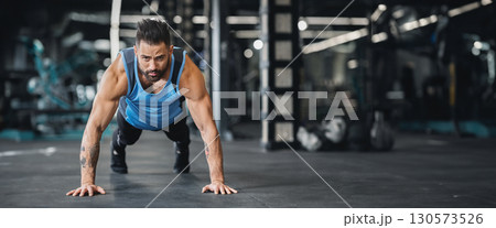 Concentrated muscular guy training in gym, doing push up exercises, free space, web-banner Concentrated muscular guy training in gym, doing push up exercises, free space, web-banner 130573526