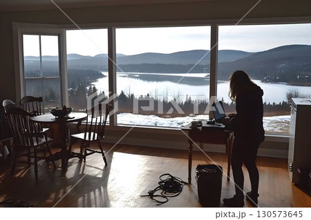 Woman working on laptop with scenic lake and mountain view from 130573645