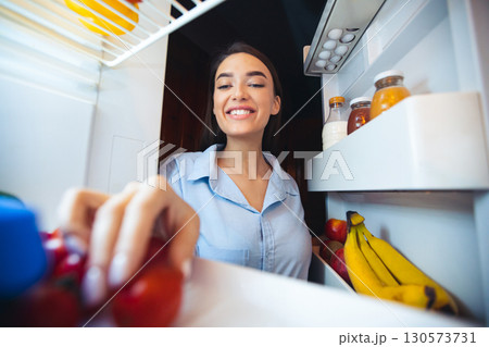 Young woman taking food from her fridge at home, view from inside, free space 130573731