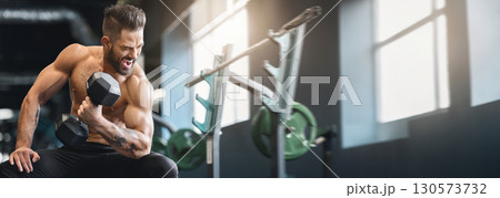Hard strength workout. Naked bodybuilder exercising with dumbbell at gym, empty space, panorama Hard strength workout. Naked bodybuilder exercising with dumbbell at gym, empty space, panorama 130573732