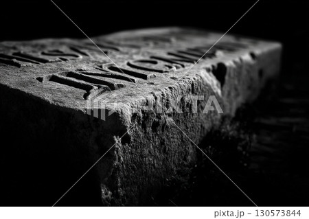 Weathered stone tablet engraved with ancient text in a dark, moody atmosphere 130573844