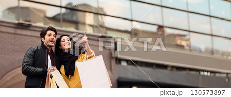 Millennial happy couple shopping together in new city, walking with paper bags and discovering city center, copy space Millennial happy couple shopping together in new city, walking with paper bags and discovering city center, copy space 130573897