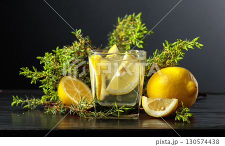 Cocktail Gin-tonic with ice, lemon, and juniper on a black background. 130574438
