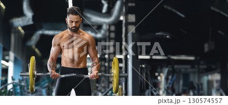 Concentrated powerlifter training with heavy barbell at gym, free space, web-banner 130574557