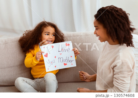Happy Mother's Day Concept. Daughter Congratulating Mother Giving Postcard Celebrating Holiday Together Sitting On Couch Indoor 130574608