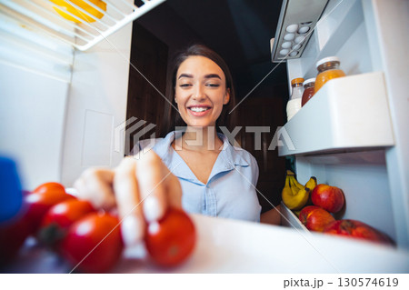 Young woman taking fresh healthy vegetables from refrigerator, view from fridge 130574619