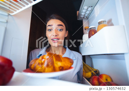 Hungry girl looking at fresh croissant in fridge, view from inside Hungry girl looking at fresh croissant in fridge, view from inside 130574632