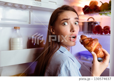 Hungry girl opening fridge, eating baking late in night, empty space Hungry girl opening fridge, eating baking late in night, empty space 130574637
